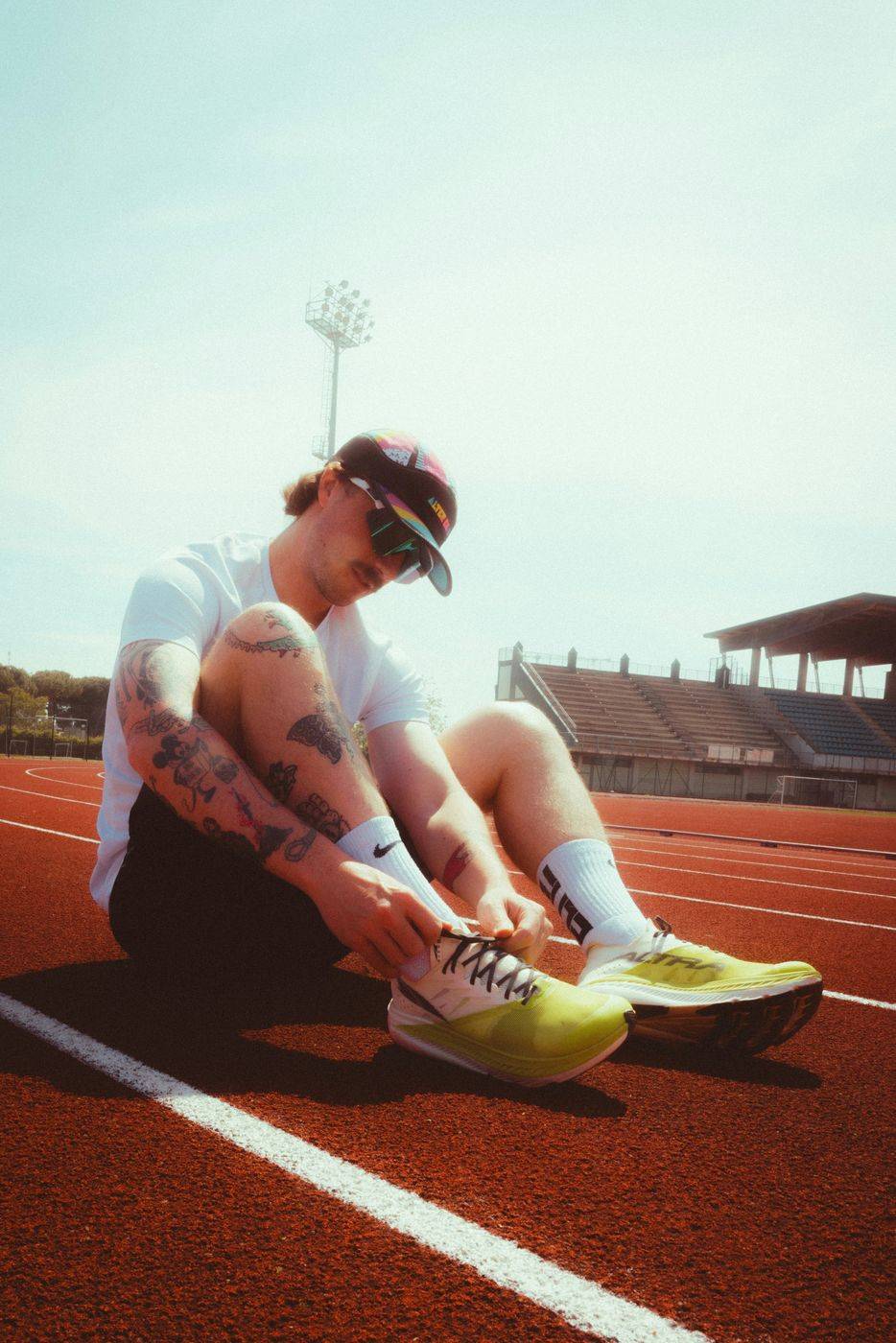 A runner tying his shoes on a track